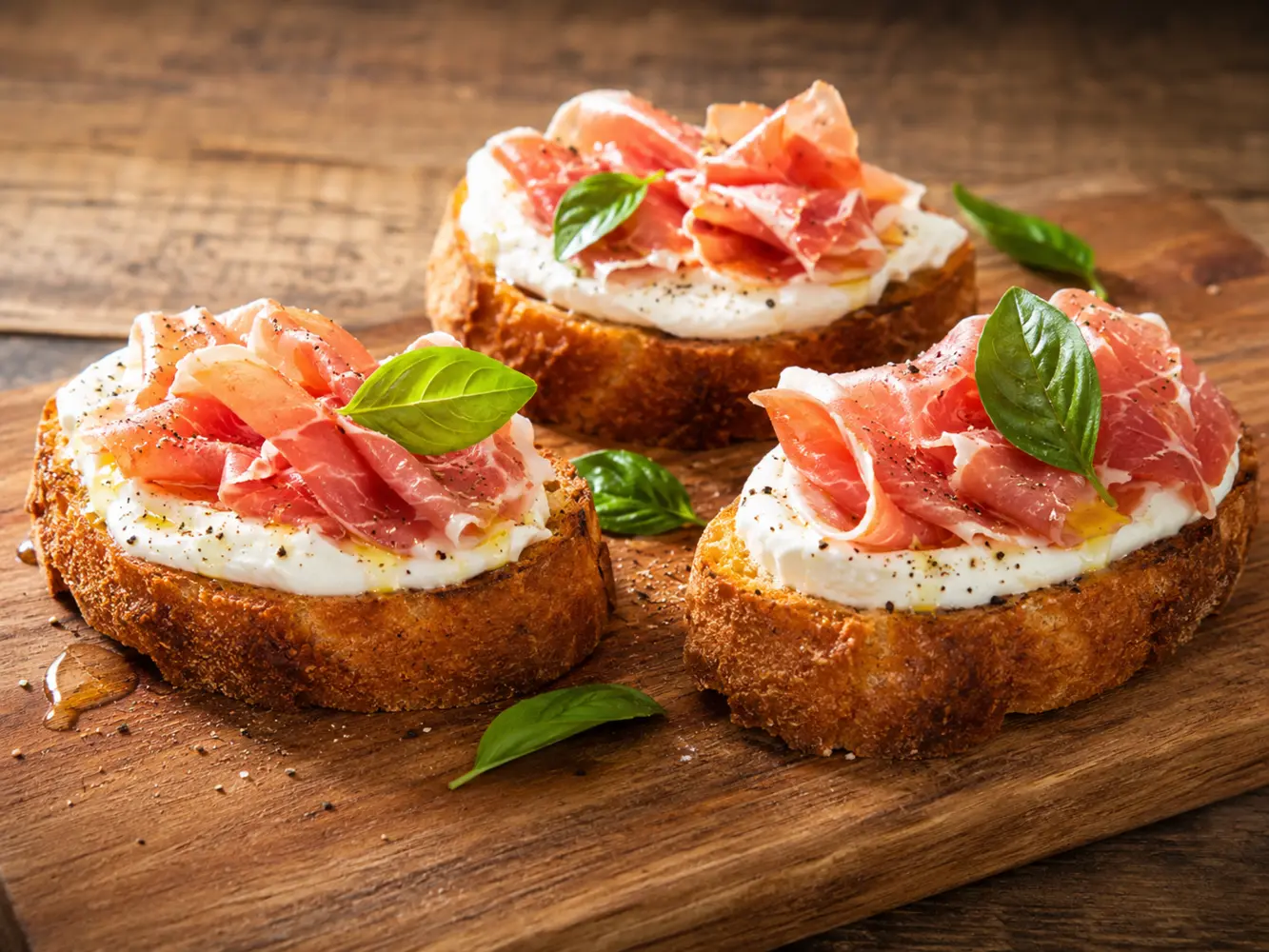 Bruschetta topped with creamy cheese and prosciutto