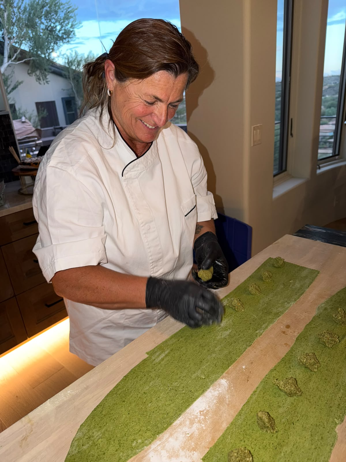 Chef Monica smiling while making fresh green ravioli by hand